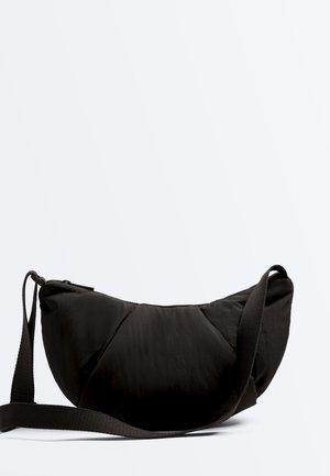 Black crescent-shaped shoulder bag with adjustable strap and zip closure, shown on a plain light background.