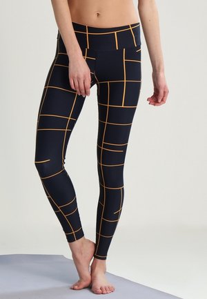 Navy leggings with a grid pattern in orange lines. Made of stretchy material, featuring a high waistband and a fitted design.