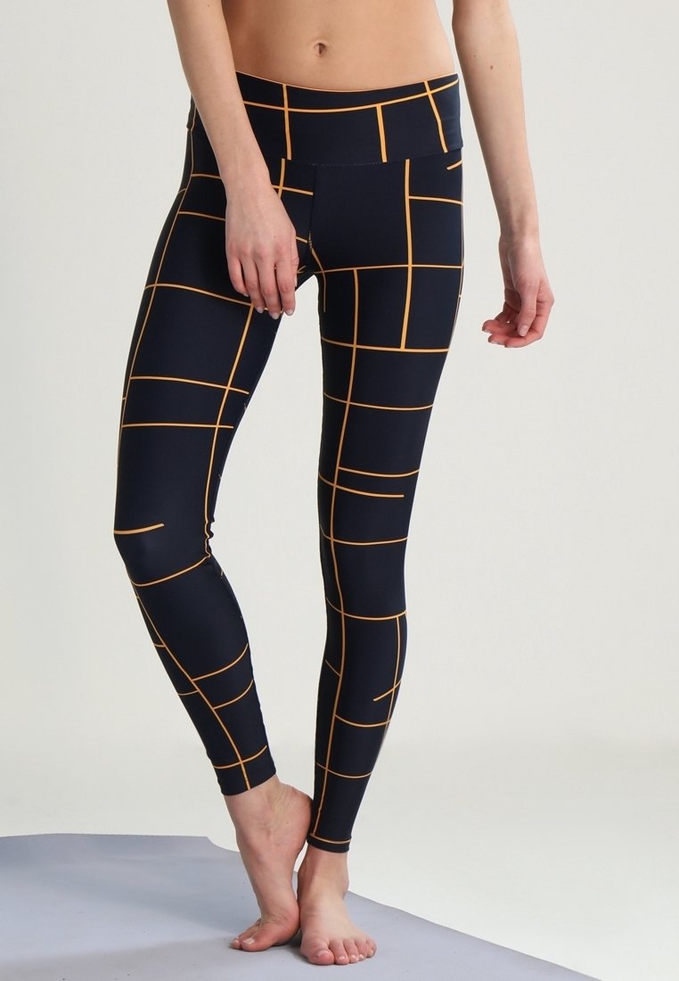 Leggings blu marina con un motivo a griglia di linee arancioni. Realizzati in materiale elasticizzato, presentano un alto punto vita e un design aderente.