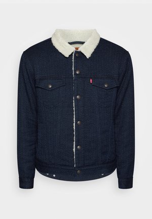 Dunkelblaue Fischgrätjacke mit weißem Sherpa-Kragen, Knopfleiste vorne, zwei Brusttaschen mit Knöpfen und eng anliegenden Bündchen.