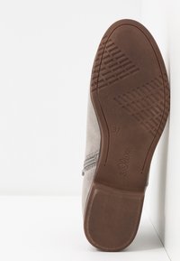 Semelle d'une chaussure en suède gris avec une semelle extérieure en caoutchouc marron, fermeture éclair sur le côté, taille 37, et marque "s.Oliver" embossée sur la semelle.