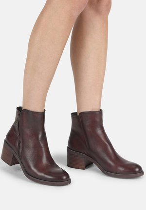 Burgundy leather ankle boots with a rounded toe, side zipper, and a stacked wooden heel, showcasing a smooth texture and fitted design.