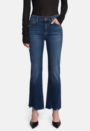 Jeans a vita alta svasati in denim blu scuro, con orli sfrangiati e design a cinque tasche, abbinati a un topo a maniche lunghe nero.
