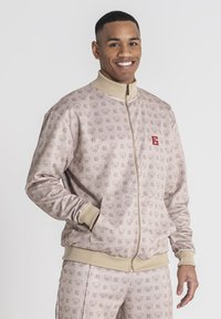 Roze zip-up jack met een herhalend patroon van logo's, ribgebreide manchetten en een hoge kraag. Beschikt over zijzakken en een klein logo op de borst.