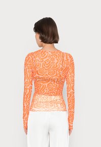 Lange mouw semi-transparante top in oranje met abstracte draaipatronen, een getailleerd silhouet en geplooide details in de taille.