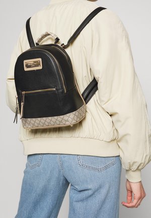 Zaino in pelle nera con forma arrotondata, base beige con motivo, ferrature dorate e manico superiore. Spallacci neri regolabili.