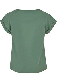 Camiseta verde oliva de manga corta con puños enrollados, mostrada desde la espalda, con un diseño sencillo y holgado.