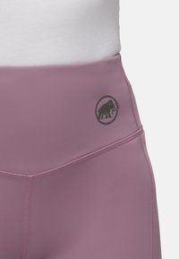 Højtaljede lilla leggings lavet af glat stof, med et sort elefantlogo på livet og flade sømme for komfort.