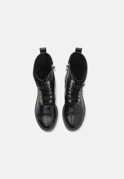 Botas de cuero negras hasta el tobillo con un acabado brillante, que cuentan con ojales plateados, cordones y una cremallera lateral. Textura suave con un diseño de punta redonda.