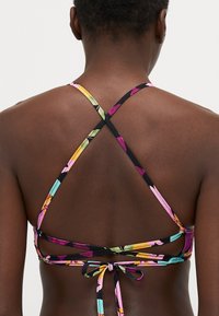 Kombinaci barevný bikini top s křížovými pásky a zavazováním na zádech. Vyrobeno z látky s živými, abstraktními vzory.