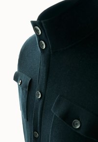 Närbild av en mörkblå skjorta med krage och två knäppta bröstfickor.