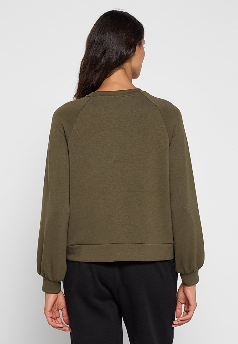 Felpa verde oliva con una vestibilità rilassata, maniche raglan e orlo a costine. Realizzata in un tessuto morbido e testurizzato per il massimo comfort.