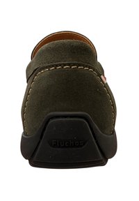 Zapato verde de ante tipo slip-on con detalles de costura, puntera redondeada y suela de goma negra que presenta el nombre de la marca "Fluchos" en el tacón.