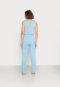 Macacão azul claro com design sem mangas, cintura elástica e detalhe em buraco na parte de trás. Feito de um tecido suave e texturizado.