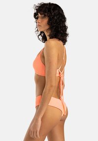 Peach ribbed bikini with a triangular top and adjustable tie-back, featuring medium-coverage bottoms in a matching shade.