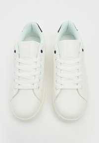 Zapatillas de piel blanca con punteras redondas, cordones planos y un diseño minimalista. Detalles en azul claro en el collar del tobillo y ojales negros.