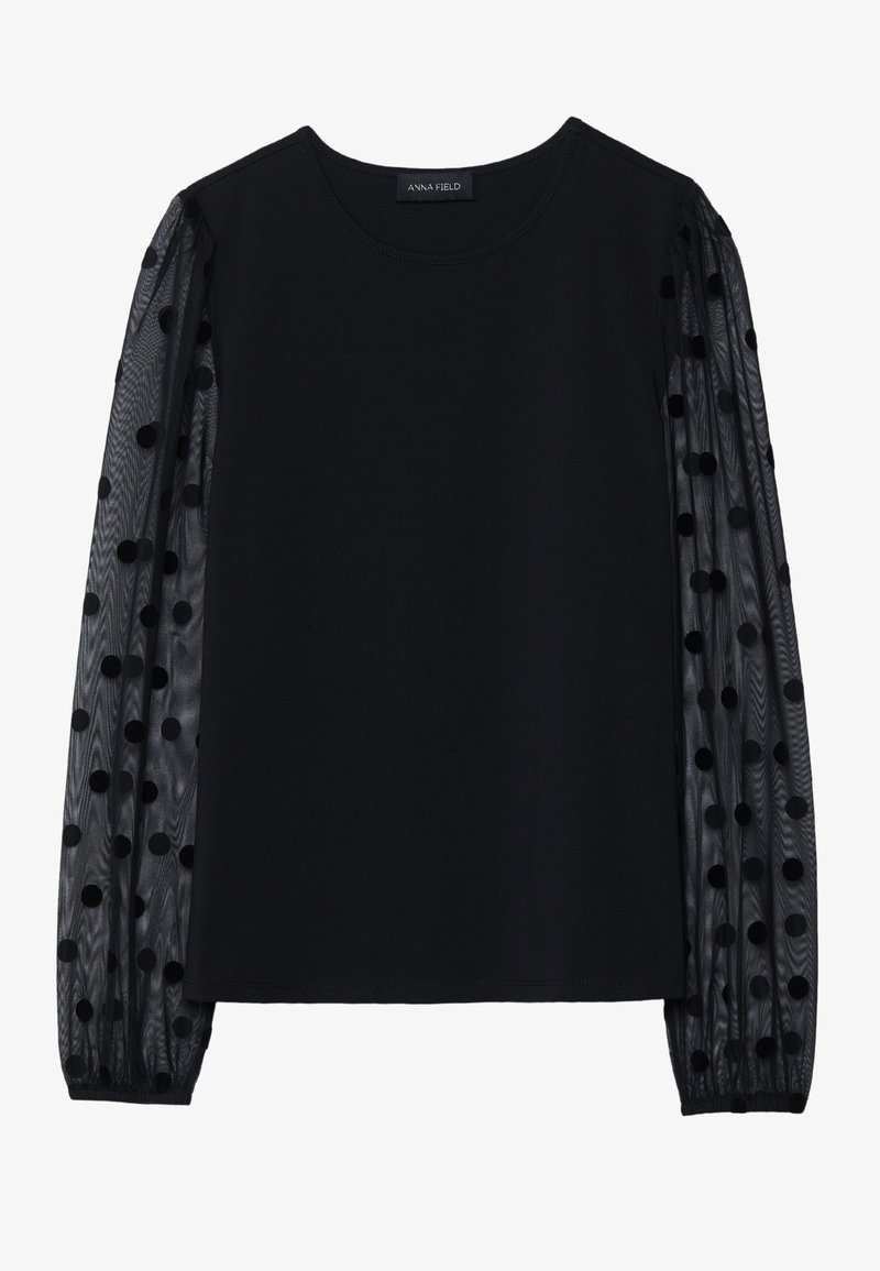 Schwarzes Top mit solidem Oberteil und transparenten, gepunkteten Ärmeln. Verfügt über einen runden Ausschnitt und Raffung an den Ärmeln.