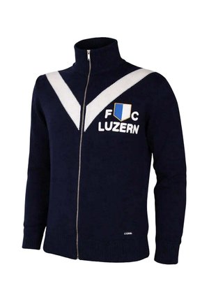 Marineblauwe ritstrui met witte V-strepen, "FC Luzern" tekst en blauw-wit schildlogo op de borst, geribbelde boorden en zoom.