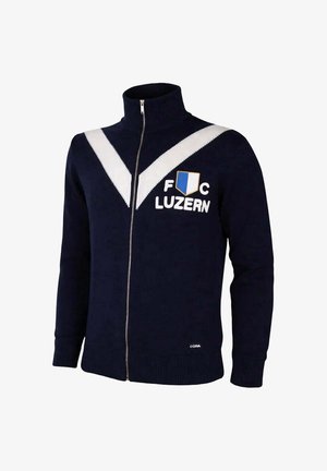 Marineblauwe ritstrui met witte V-strepen, "FC Luzern" tekst en blauw-wit schildlogo op de borst, geribbelde boorden en zoom.