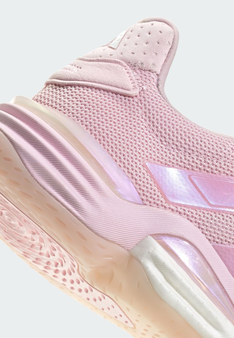 Zapatilla deportiva rosa con una parte superior de malla y acentos brillantes, superficie texturizada y una suela gruesa y moteada para tracción y soporte.