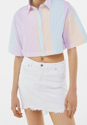 Krótka koszula zapinana na guziki w pastelowe paski w kolorach fioletowym, pomarańczowym i niebieskim; zestawiona z postrzępioną białą spódnicą z denimu.