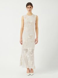 Robe sans manches, longue jusqu'au sol, en beige clair avec broderies florales. Couche inférieure transparente avec des détails texturés. Chaussures à talons hauts blanches.