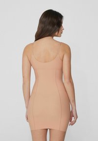Tělové šaty těsně přiléhající k tělu s tenkými ramínky, hladkou texturou a délku po stehna. Obsahují šité švy a bezešvou zadní část.