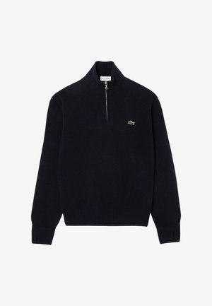 Pulover tricotat de culoare bleumarin, cu guler cu fermoar, manșete și tiv cu nervuri. Prezintă un mic logo verde Lacoste pe piept.