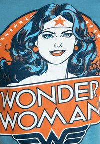 Blue t-shirt featuring a graphic of Wonder Woman. Design includes her face, orange accents, a star headband, and bold text "WONDER WOMAN."