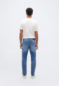 Τζιν παντελόνι από ανοιχτό μπλε ντένιμ με άνετη εφαρμογή, πίσω τσέπες και καφέ δερμάτινο λογότυπο στη μέση. Συνδυασμένο με κρεμ μπλούζα.