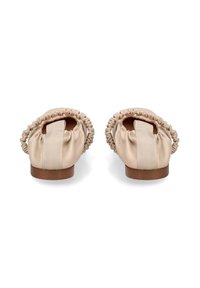 Ballerine beige con retro in elastico arricciato e ampie linguette in tessuto, con suole piatte marroni, viste da dietro.