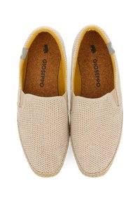 Zapatillas beige claro de tipo slip-on con una parte superior de malla texturizada, plantilla de corcho, forro interior amarillo y un acento gris en el lado. Suela de goma.