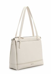 Światłobeżowa torebka z wegańskiej skóry o strukturalnym designie, wyposażona w dwa długie paski, górny zamek błyskawiczny oraz małą przednią kieszeń.