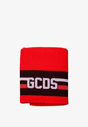 Punainen taitettu kangas, jossa mustavalkoiset vaakasuorat raidat ja valkoiset kirjaimet "GCDS" mustalla raidalla keskellä.