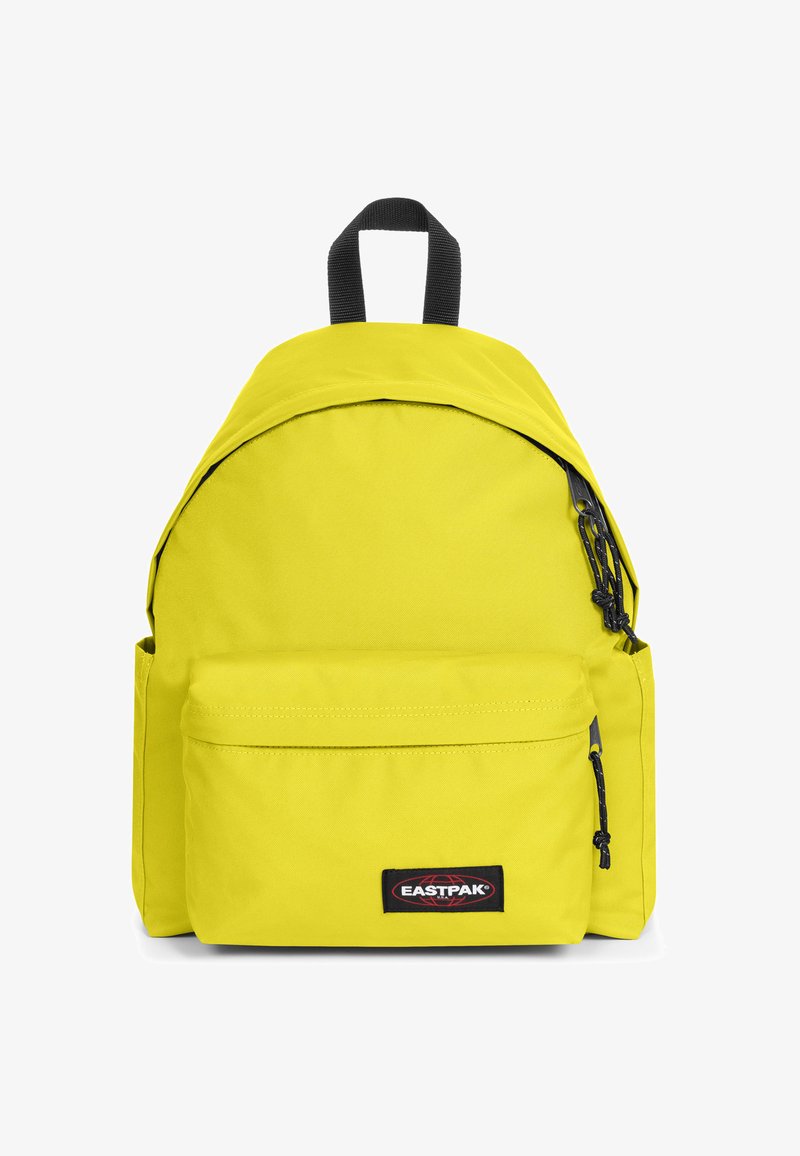 Sac à dos jaune vif en tissu résistant, doté d'une forme arrondie, d'une poche avant, d'un patch logo, ainsi que de fermetures éclair et accents noirs.