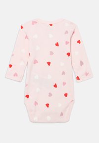 Lys rosa langermet babybody med spredte mønstre av røde, rosa og hvite hjerter. Mykt bomullsmateriale med rund hals.