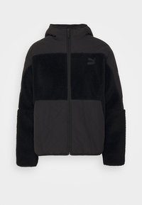 Veste à capuchon noire avec un design matelassé sur la moitié supérieure et une texture en polaire douce sur la moitié inférieure. Fermeture éclair à l'avant.
