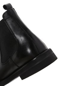 Stivale Chelsea in pelle nera con pannelli laterali elasticizzati, punta arrotondata e suola in gomma; finitura elegante con dettagli minimi e costruzione robusta.