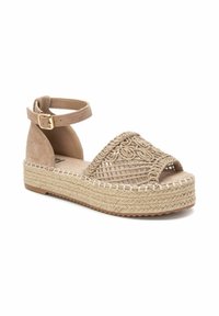 Sandalias de espadrilles beige con parte superior trenzada, punta abierta y tira alrededor del tobillo. Suela de plataforma de yute natural con detalles de costura en contraste.