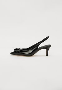 Svart patentlær slingback-sko med spiss tå, liten hæl og en fremtredende sløyfe på vampsiden. Glatt tekstur og elegant design.