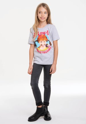 Gray t-shirt featuring a colorful graphic of a girl with orange pigtails and the text "Pippi Långstrump." Paired with dark skinny jeans and black boots.