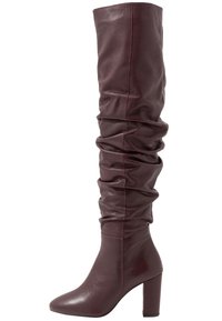 Botas de cuero burdeos hasta la rodilla con un diseño arrugado y un tacón de bloque. Presenta una punta afilada y detalles de costura mínimos.