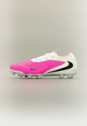 Gheată de fotbal Nike albă și roz cu logo-uri negre Swoosh și crampoane turnate pe talpă, concepută pentru joc pe teren tare.