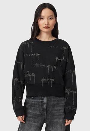 Felpa nera con testo "All Saints" ricamato in argento, colletto a girocollo, vestibilità rilassata e maniche lunghe, abbinata a jeans in denim sbiaditi.