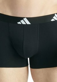 Czarne bokserki męskie wykonane z rozciągliwego materiału. Posiadają szeroki czarny pas z białym logo w trzy paski. Gładka tekstura, dopasowany krój.