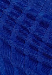 Strickstoff in einem tiefen Blau mit strukturierten, gerippten Mustern, die erhabene Bereiche und glatte Flächen kombinieren und so einen visuellen Kontrast und Tiefe erzeugen.