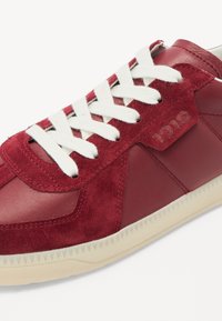 Røde lær- og suedeforede sneakers med hvite snørebånd og teksturert gummisåle med bølgekant. Embossert logodetalj på siden.