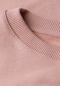 Ljusrosa bomullströja med ribbad rund halsringning, slät yta och plana sömmar. Avslappnad design utan synliga mönster eller detaljer.