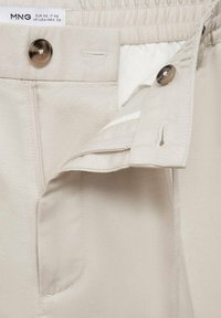 Beige broek van een katoenmix, met een ritssluiting aan de voorkant, knoopsluiting en zak. Voorzien van een elastische tailleband voor comfort.