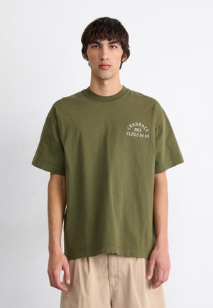 Camiseta de algodón verde oliva con mangas cortas, cuello redondo y texto blanco que dice "Carhartt 89 Clase de." Diseño simple y de corte relajado.